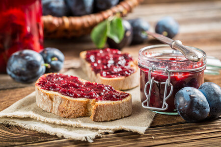 The Easiest Way to Make Homemade Jelly and Jam 16 small jar of homemade jam next to sourdough bread spread with thick red jam.
