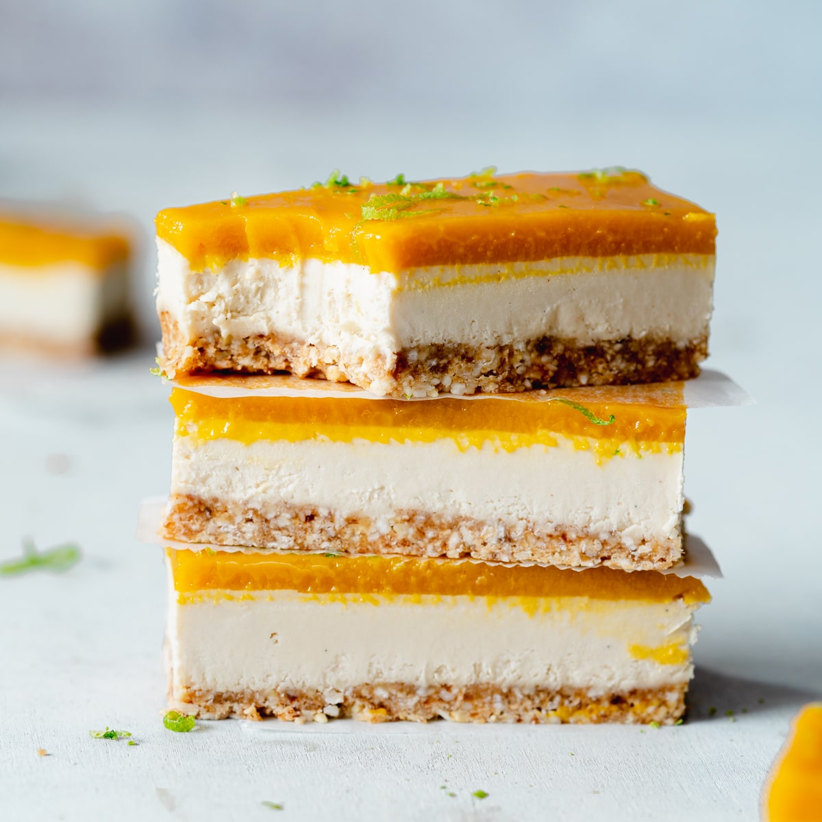 Don't Miss These Recipes Using Coconut Yogurt 8 3 mango and coconut yogurt bars are stacked up. They have biscuit base and mango topping with lime zest.